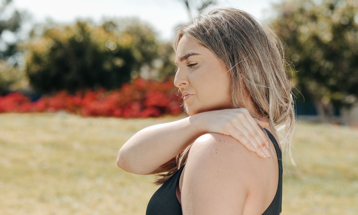 A woman holding her shoulder, showing joint discomfort