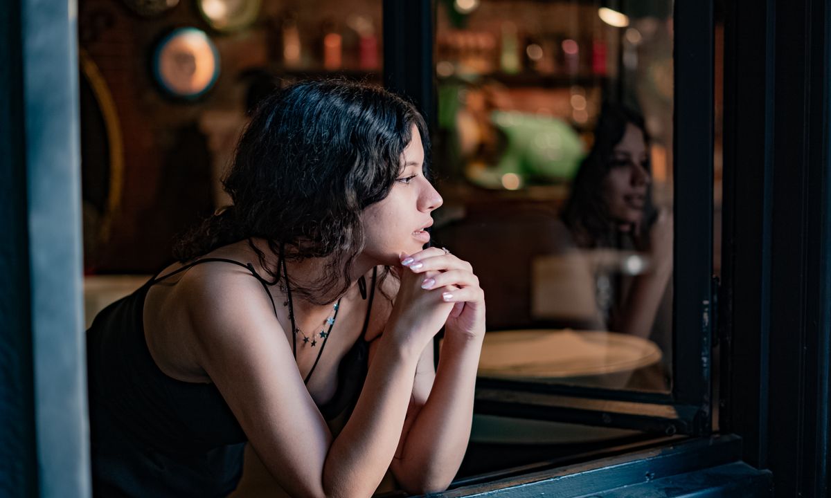 A woman sitting quietly by a window, looking thoughtful