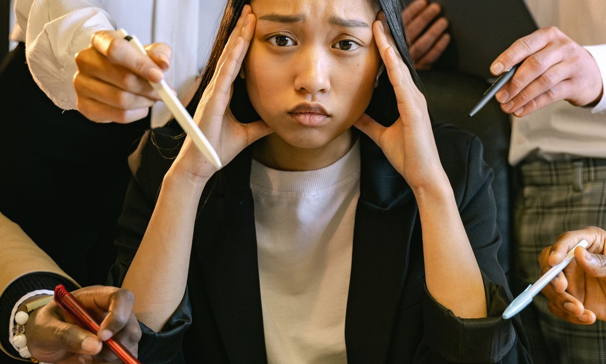 A woman with her hand to her forehead, looking tense and overwhelmed