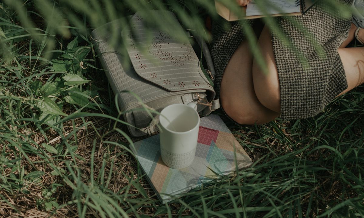 A woman writing in a journal with a warm drink, looking calm and reflective