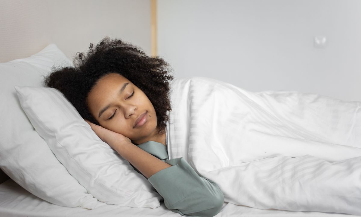 A woman sleeping peacefully in a calm, bright bedroom