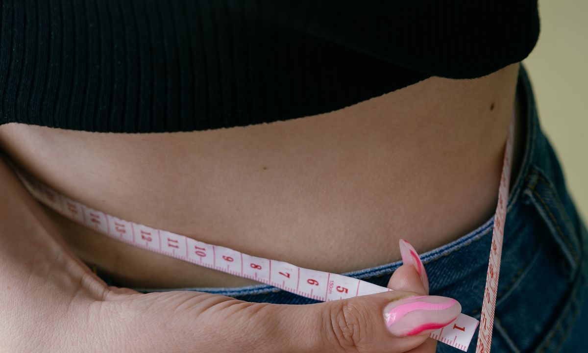 A woman measuring her waist with a tape measure